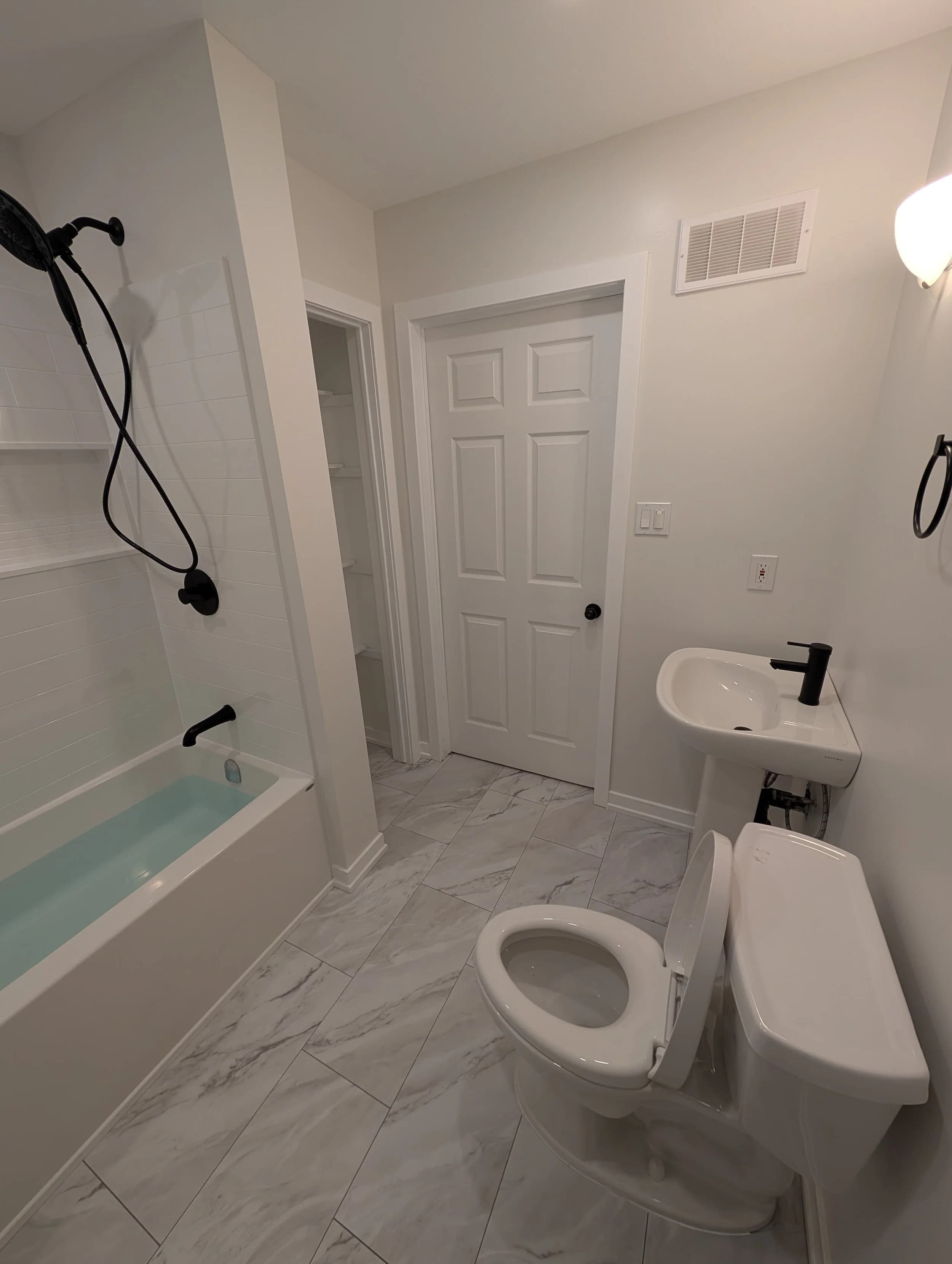 Compact bathroom refresh with marble-look tile floor and tub/shower.