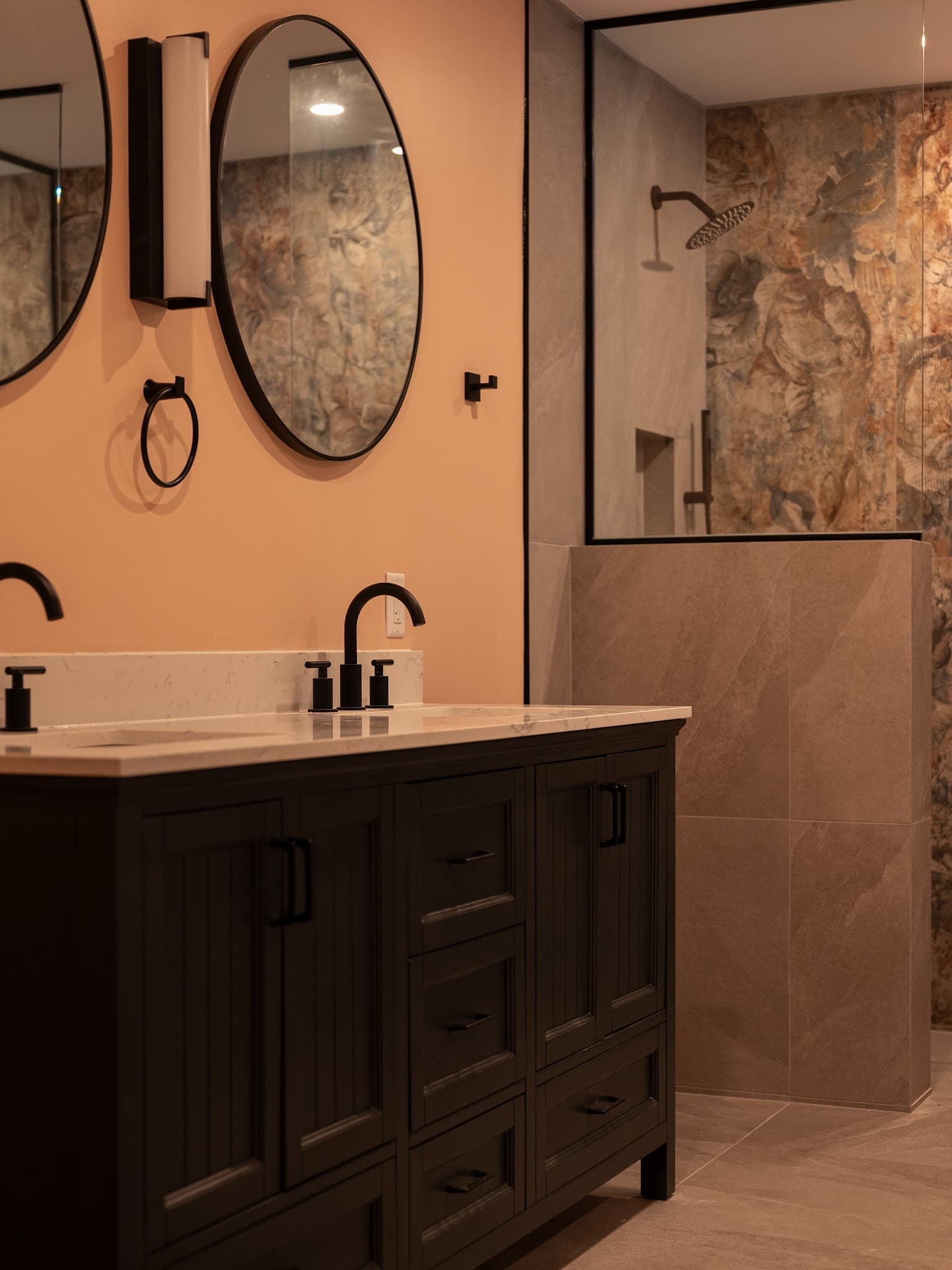 Walk-in shower with watercolor floral feature tile and matte black rainfall fixture.