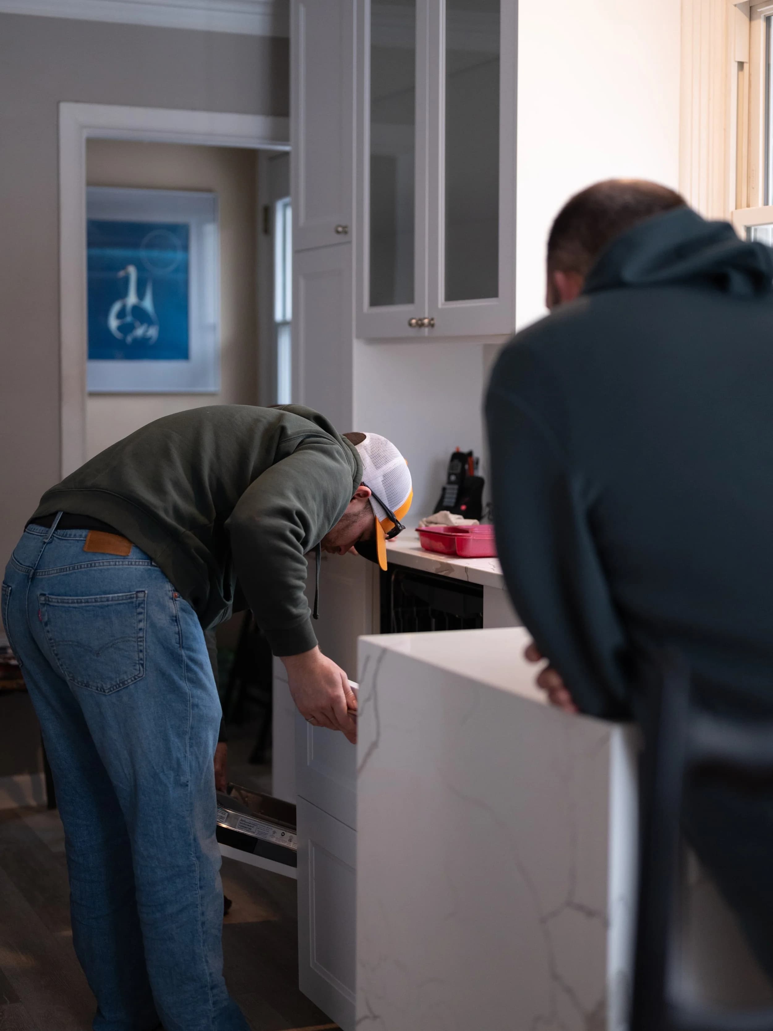 J Squared craftsmen installing a custom quartz countertop on a kitchen island.